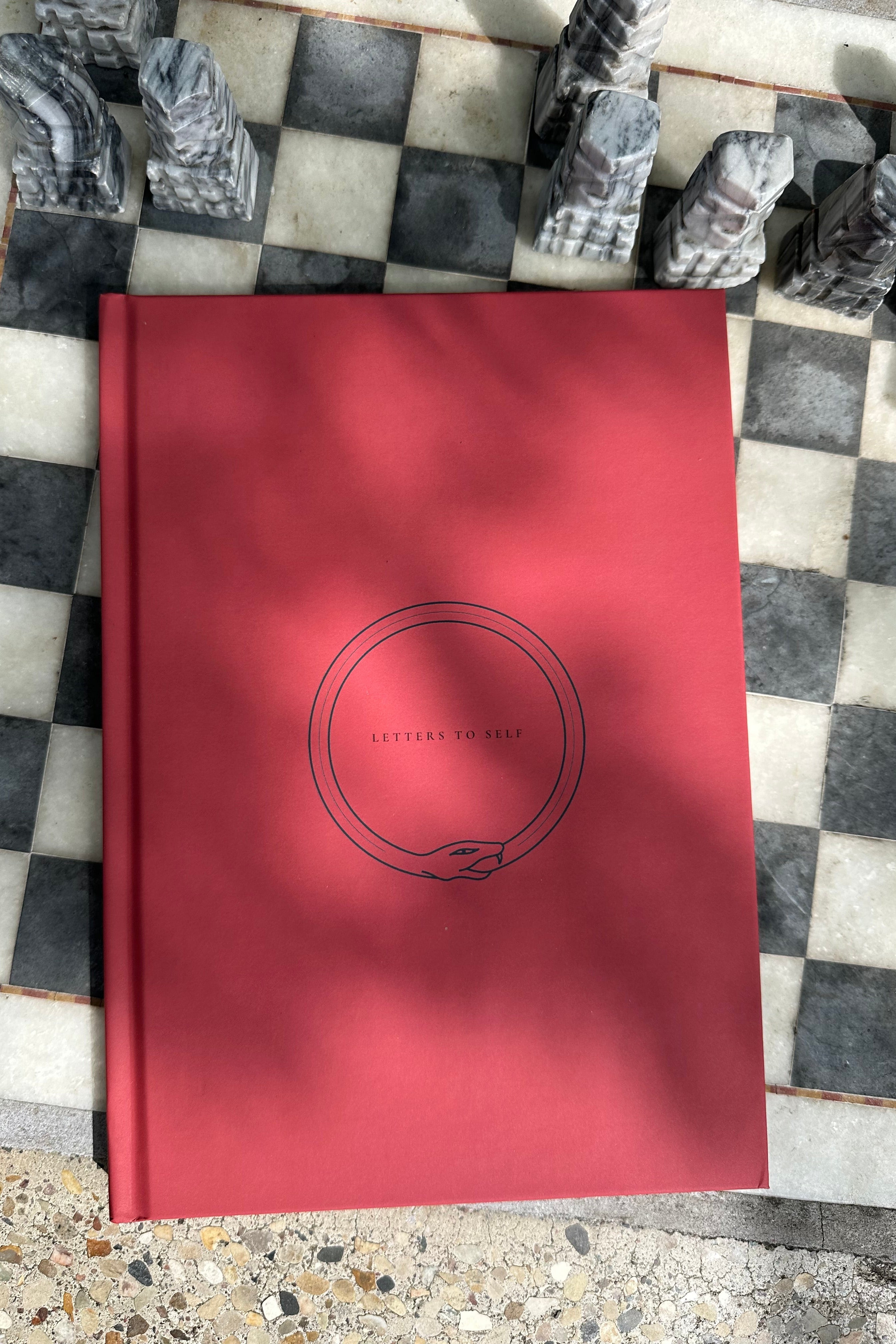 Red guided journal notebook on a chess board.